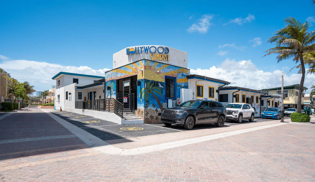 Hollywood Sunrise Hotel exterior with its ocean mural and rooftop sign under a blue sky