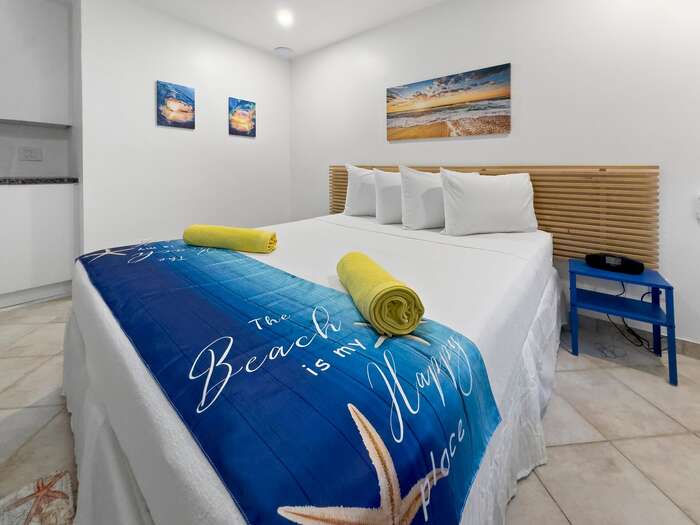 King bed studio with headboard, coastal art and yellow accent towels