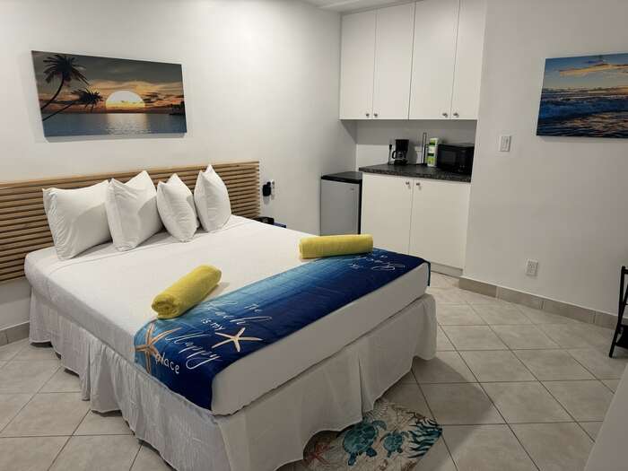 Suite with bed and open kitchenette with cabinets and coffee station
