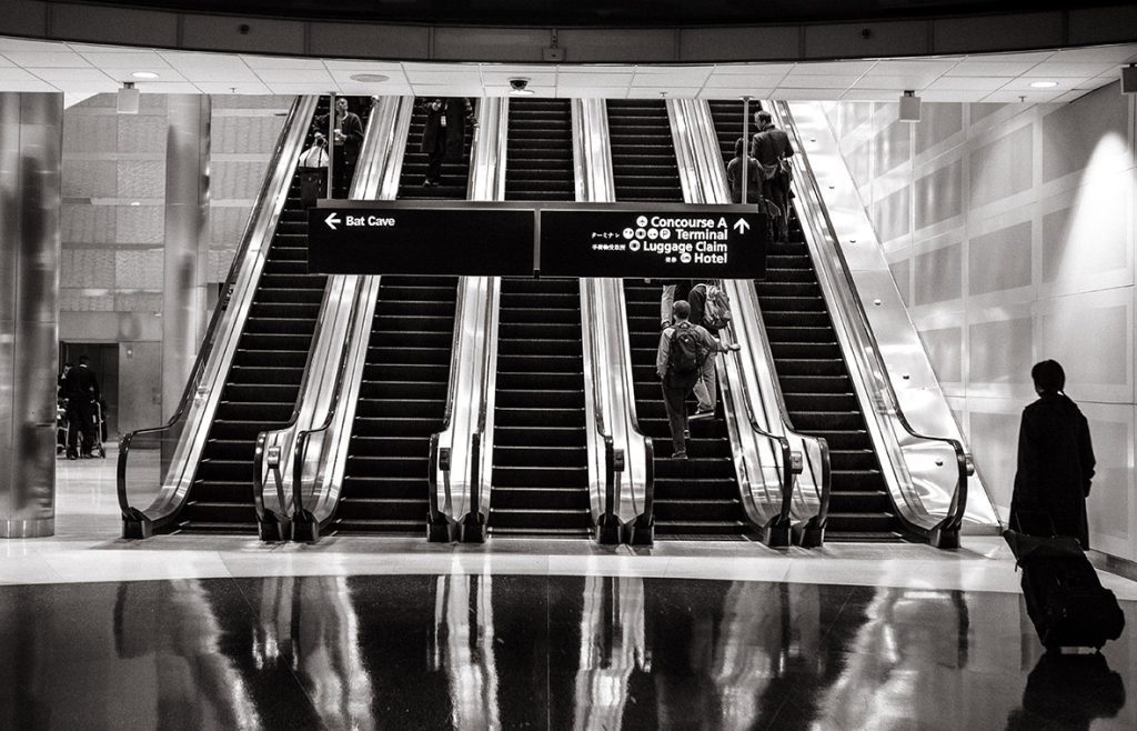 A black and white photo of people on escalators.