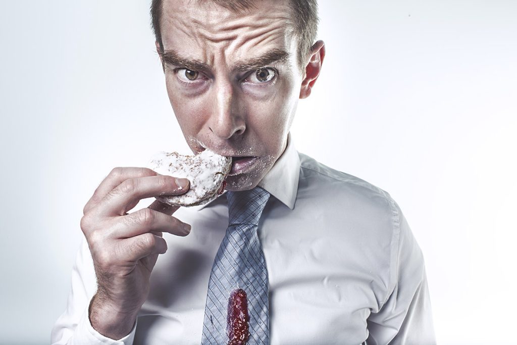 A man in a tie eating something with his mouth.