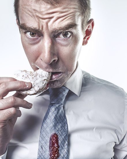 A man in a tie eating something with his mouth.