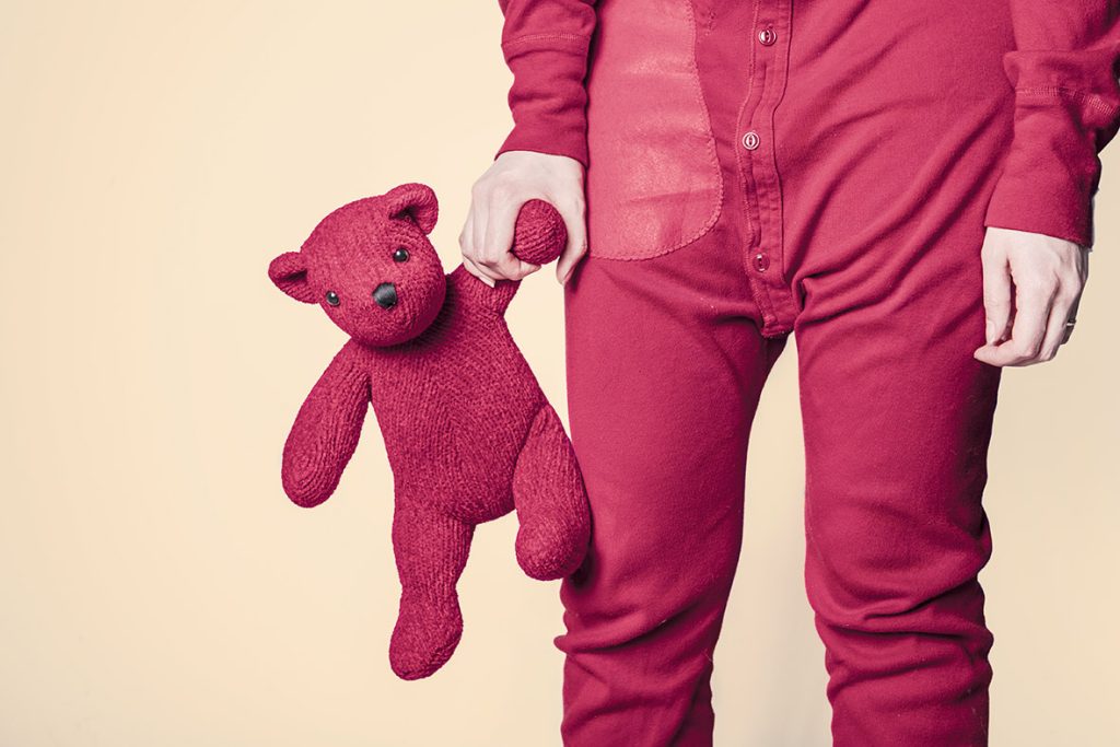 A person in pink pants holding a teddy bear.