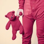 A person in pink pants holding a teddy bear.