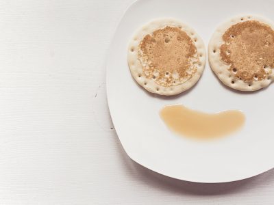 A plate with two pancakes and syrup on it